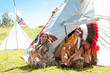 North American Indians sit at a wigwam