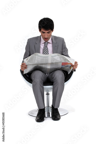 Photo: Businessman looking in shock at his newspaper Businessman looking in shock at his newspaper