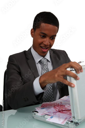 Photo: A con man opening a case full of money A con man opening a case full of money