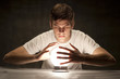 Studio shot of young man with hands around glowing crystal ball