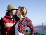 Photo: "USA, California, San Francisco, young couple kissing, Golden Gate Bridge in background" "USA, California, San Francisco, young couple kissing, Golden Gate Bridge in background"