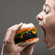 "Side view of young man about to bite a tire hamburger, close up"