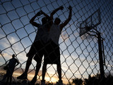 Photo: "USA, Utah, Salt Lake City, three young men playing street basketball, low angle view" "USA, Utah, Salt Lake City, three young men playing street basketball, low angle view"