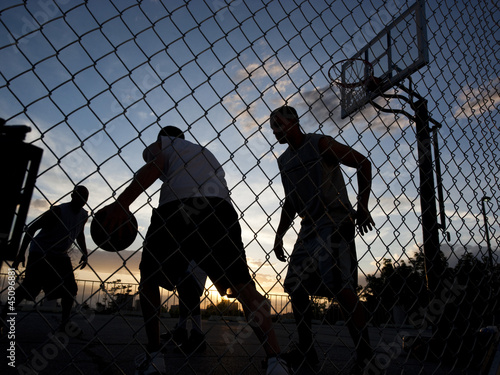Photo: "USA, Utah, Salt Lake City, four young men playing street basketball, low angle view" "USA, Utah, Salt Lake City, four young men playing street basketball, low angle view"