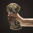 Young woman's hand holding a wad of US one dollar bills