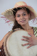 Woman wearing a straw hat and playing the djembe