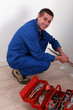 Photo: Plumber kneeling by tool box Plumber kneeling by tool box