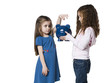 Studio shot of girl (4-5) inserting money to piggy bank held by sister (6-7)