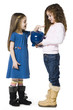 Studio shot of girl (4-5) inserting money to piggy bank held by friend (6-7)