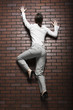 Studio shot of young woman climbing up brick wall