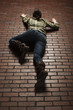 Studio shot of young woman climbing up brick wall