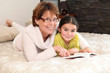 little girl reading a book with her granny