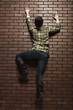Studio shot of young woman climbing up brick wall