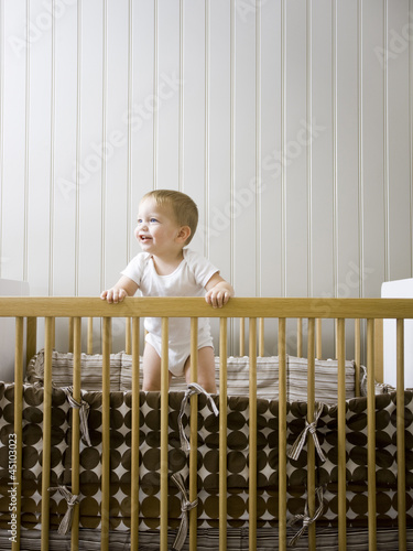 Photo: "USA, Utah, Provo, Baby boy (18-23 months) standing in crib" "USA, Utah, Provo, Baby boy (18-23 months) standing in crib"