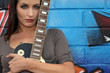 Female guitarist standing in front of graffiti