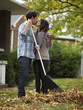 "USA, Utah, Provo, Young couple kissing, raking leaves in garden"