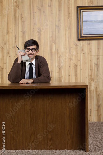 Photo: Businessman using old fashioned mobile phone in office Businessman using old fashioned mobile phone in office