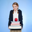 Studio portrait of girl (10-11) holding stack of books and apple