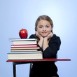 Studio portrait of girl (10-11) with stack of books and apple