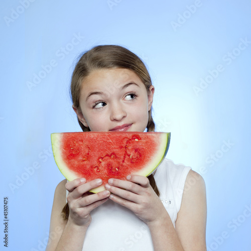 Photo: Studio shot of girl (10-11) holding slice of watermelon Studio shot of girl (10-11) holding slice of watermelon