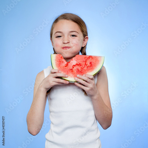 Photo: Studio shot of girl (10-11) eating watermelon Studio shot of girl (10-11) eating watermelon