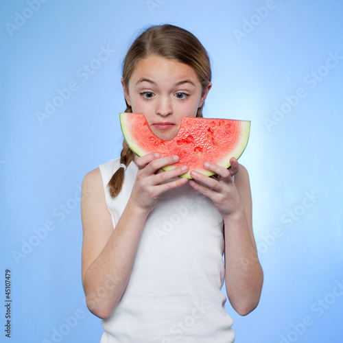 Photo: Studio shot of girl (10-11) holding slice of watermelon Studio shot of girl (10-11) holding slice of watermelon