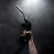 Studio shot of man's hand with blood holding gasoline nozzle