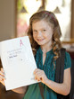 Photo: "USA, Utah, Cedar Hills, Girl (8-9) holding book of examination results with A grade" "USA, Utah, Cedar Hills, Girl (8-9) holding book of examination results with A grade"