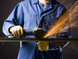 man in blue coveralls with a power grinder