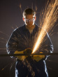 man in blue coveralls with a power grinder