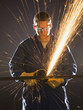 man in blue coveralls with a power grinder