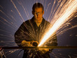 man in blue coveralls with a power grinder