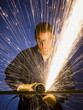 man in blue coveralls with a power grinder