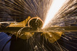 man in blue coveralls with a power grinder