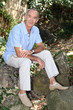 Old man sat on a rock in his garden