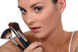 woman holding three make up brushes