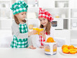 Little chefs making fresh orange juice in the kitchen