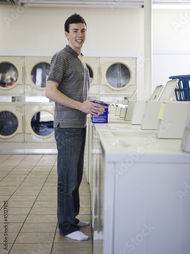 Photo: man doing laundry at a laundromat man doing laundry at a laundromat