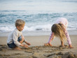 brother and sister playing in the sand at the beach