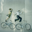 Photo: "USA, Utah, Salt Lake City, Couple lying holding hands and lying on pavements with their bikes" "USA, Utah, Salt Lake City, Couple lying holding hands and lying on pavements with their bikes"