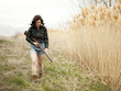 "USA, Utah, Orem, Woman with rifle walking on meadow"