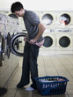 man taking off clothes at a laundromat