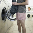 man taking off clothes at a laundromat