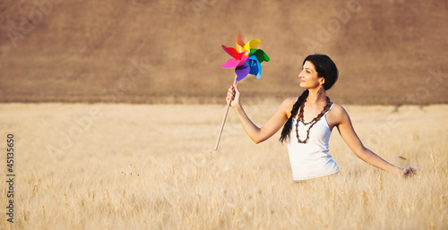Photo: Young beautiful woman in a wheat field with windmill. Young beautiful woman in a wheat field with windmill.