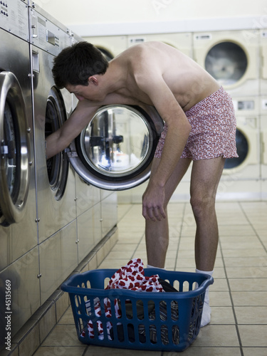 Photo: man taking off clothes at a laundromat man taking off clothes at a laundromat