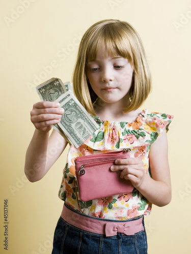 Photo: little girl putting money in her pink wallet little girl putting money in her pink wallet