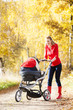Photo: woman with a pram on walk in autumnal alley woman with a pram on walk in autumnal alley