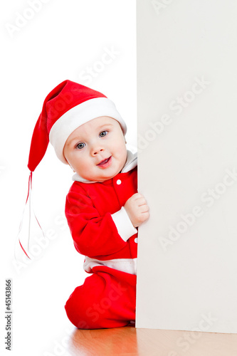 Photo: small Santa claus child looking from behind the placard small Santa claus child looking from behind the placard