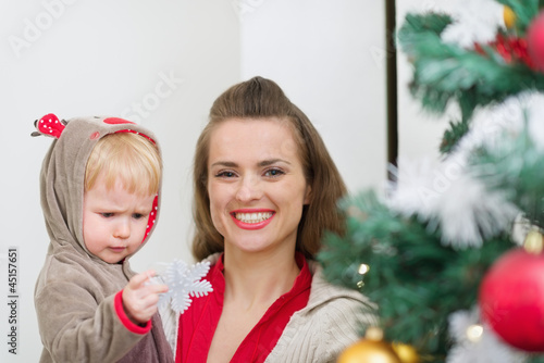 Photo: Baby helping mother decorate Christmas tree Baby helping mother decorate Christmas tree
