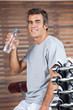 Happy Man Drinking Water From Bottle At Health Club